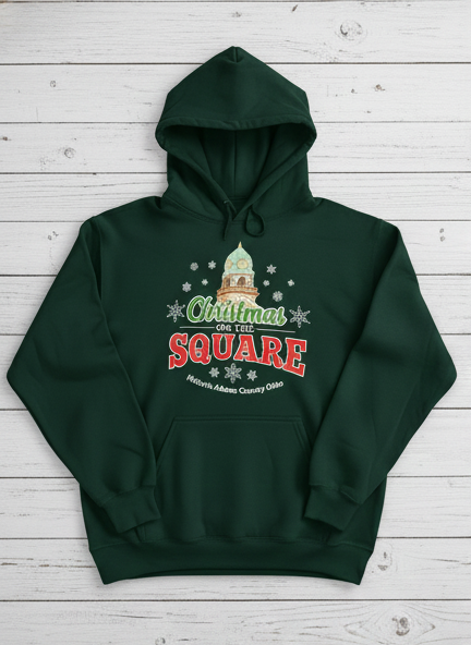 Green hoodie with 'Christmas on the Square' design on a wooden surface